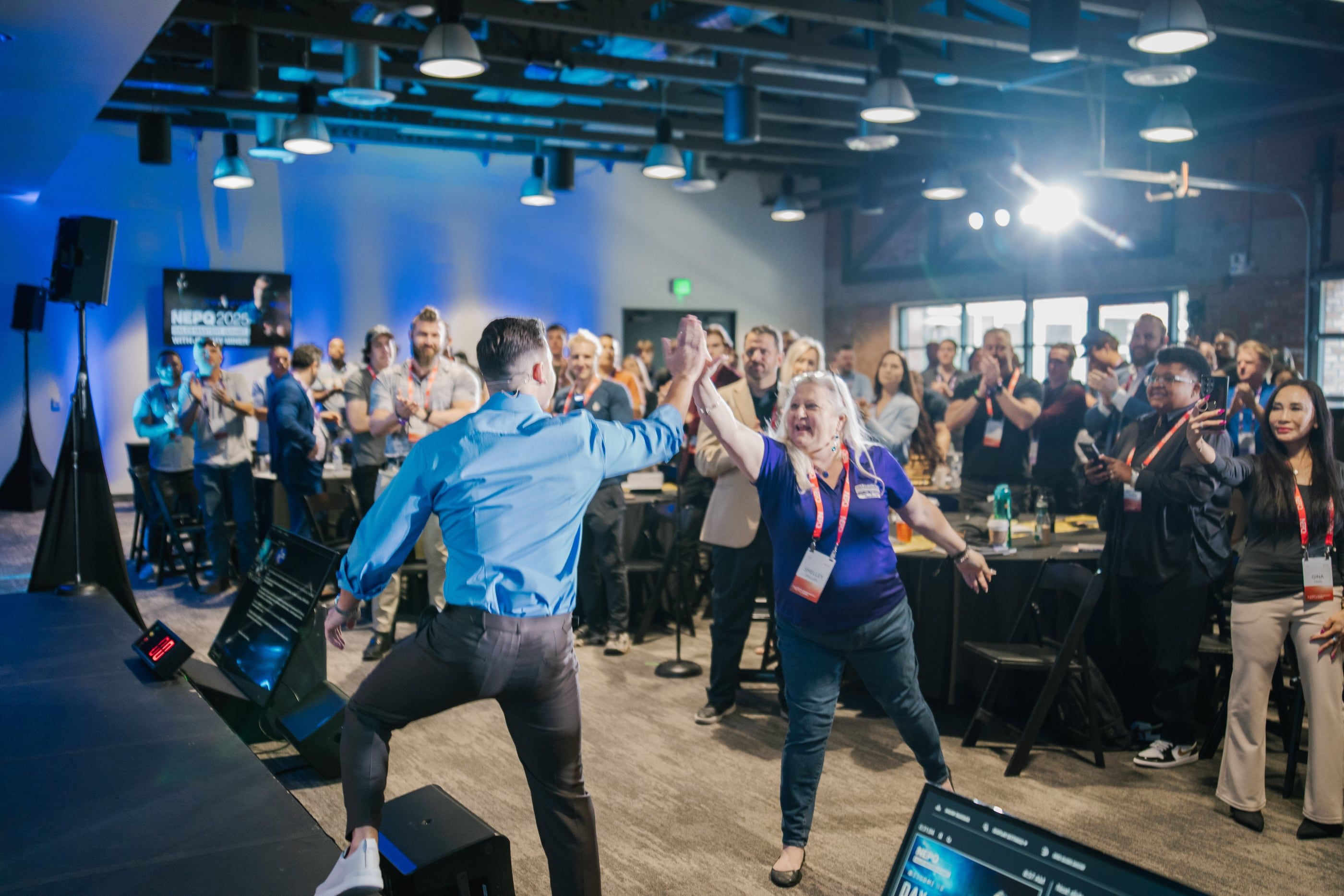 A presenter and an attendee high-fiving in front of a cheering room